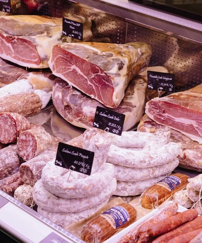Jambons et salaisons dans la vitrine du comptoir Saporini